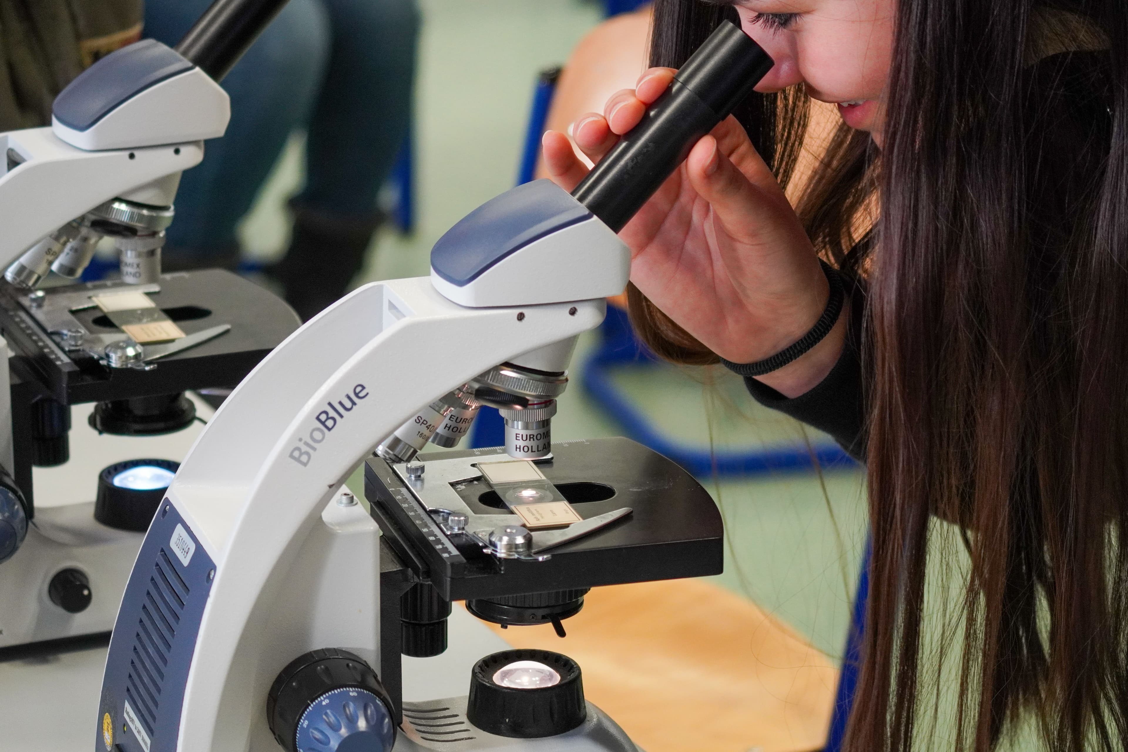 a woman is looking through a microscope in a classroom .
