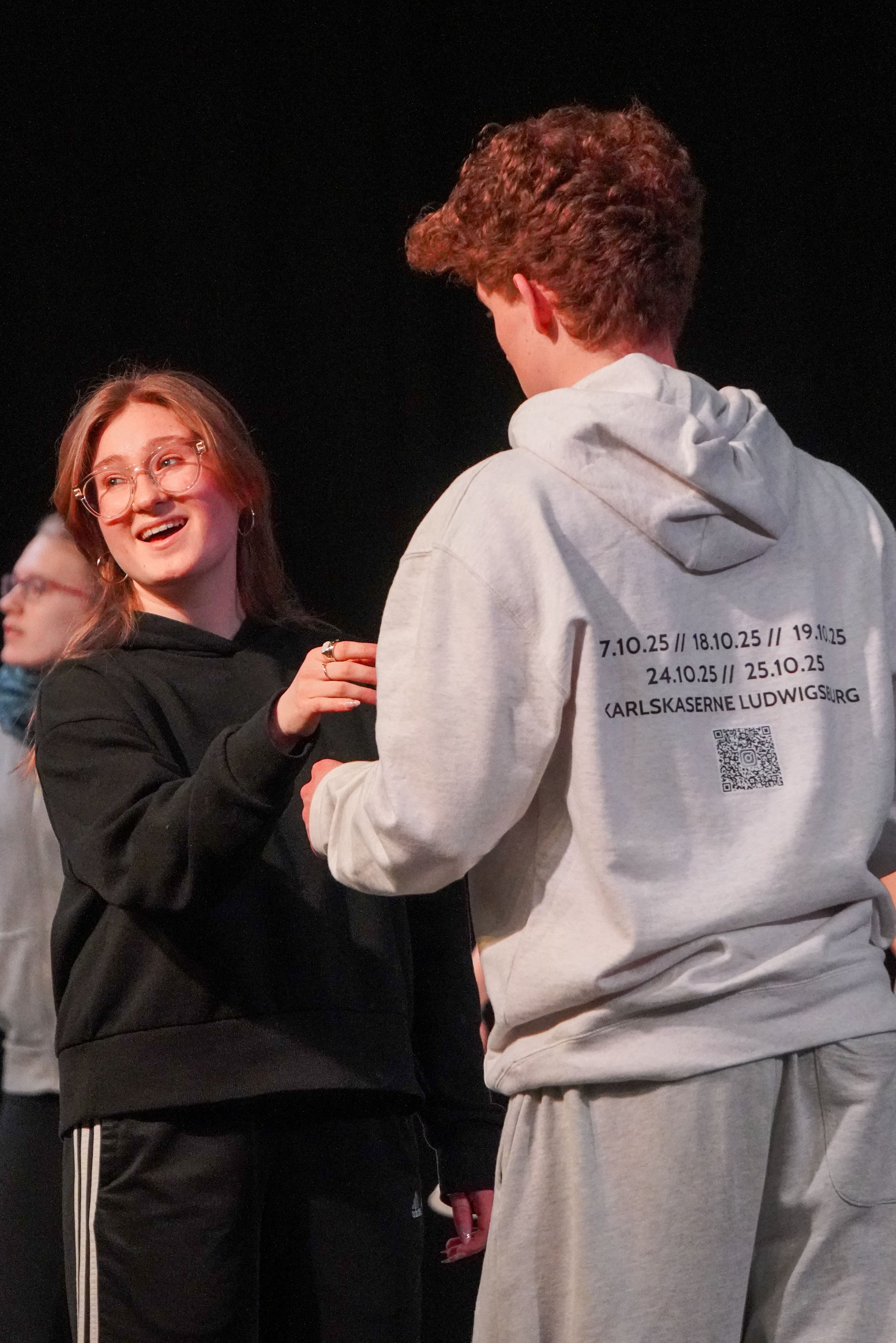 Ein Mädchen und ein Junge stehen sich während einer Theaterprobe auf einer Bühne gegenüber.