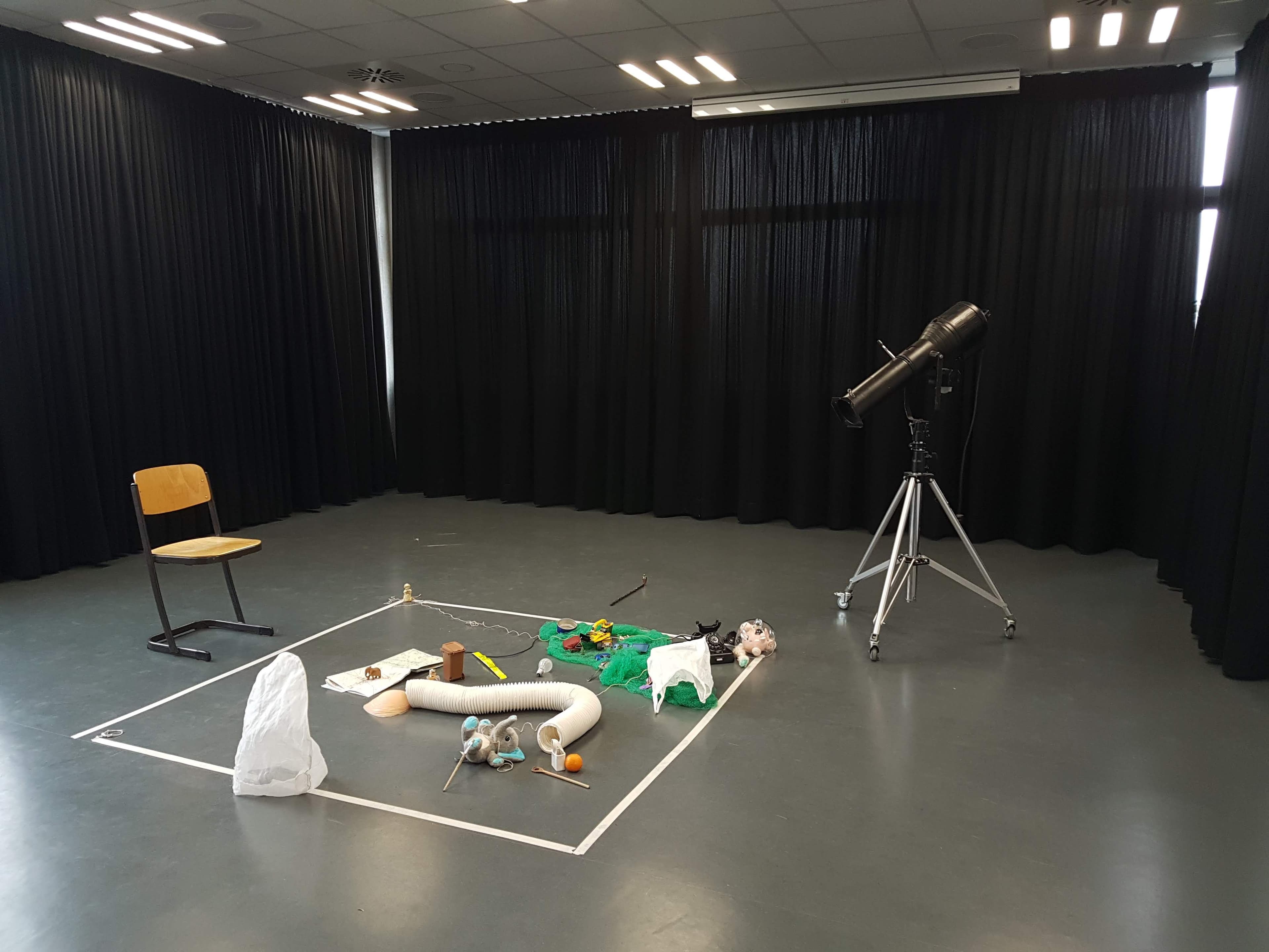 Raum mit abgeklebter Bühne, Gegenständen, Stuhl und Fernglas