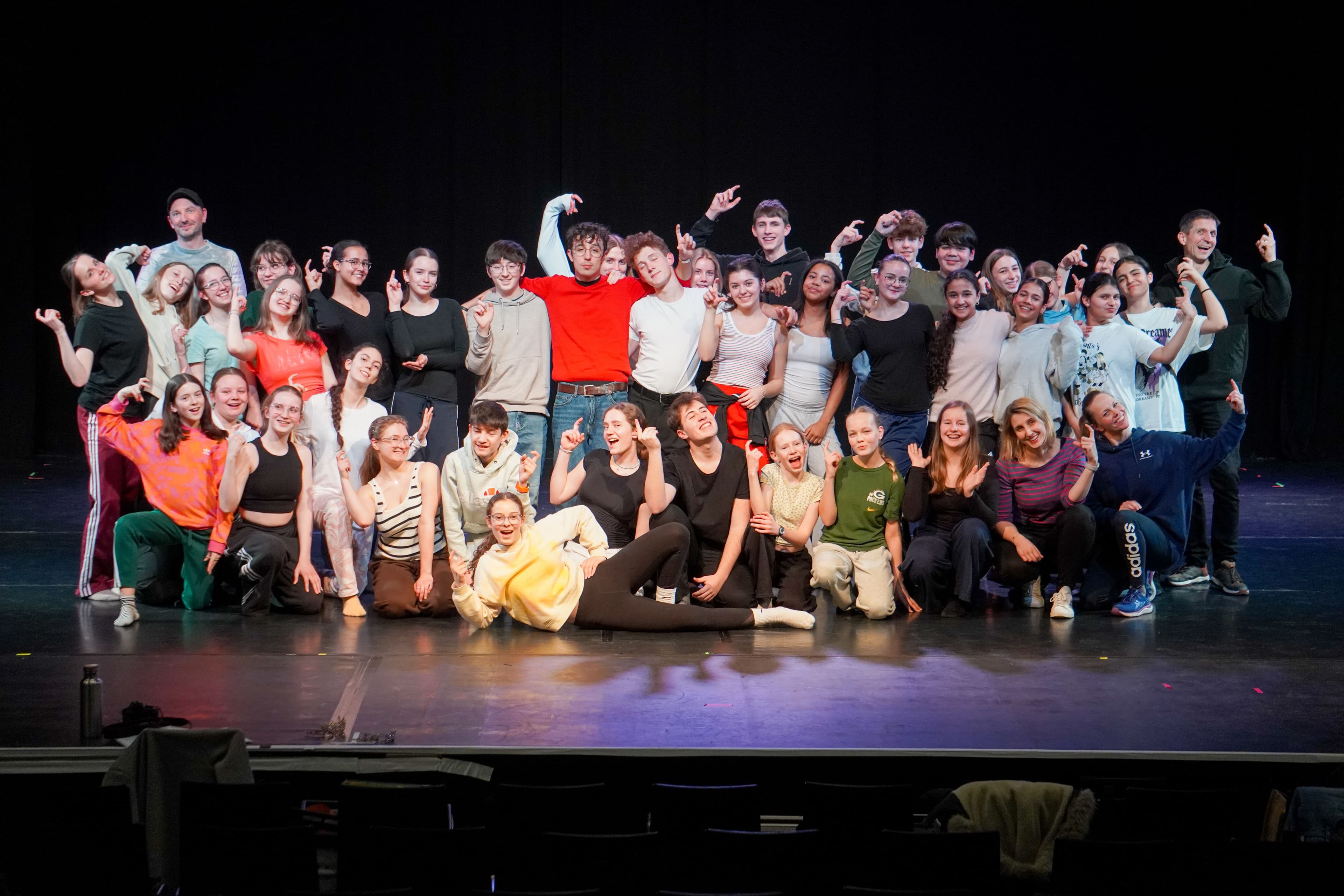 Musical-Ensemble posiert für ein Foto auf einer Bühne.