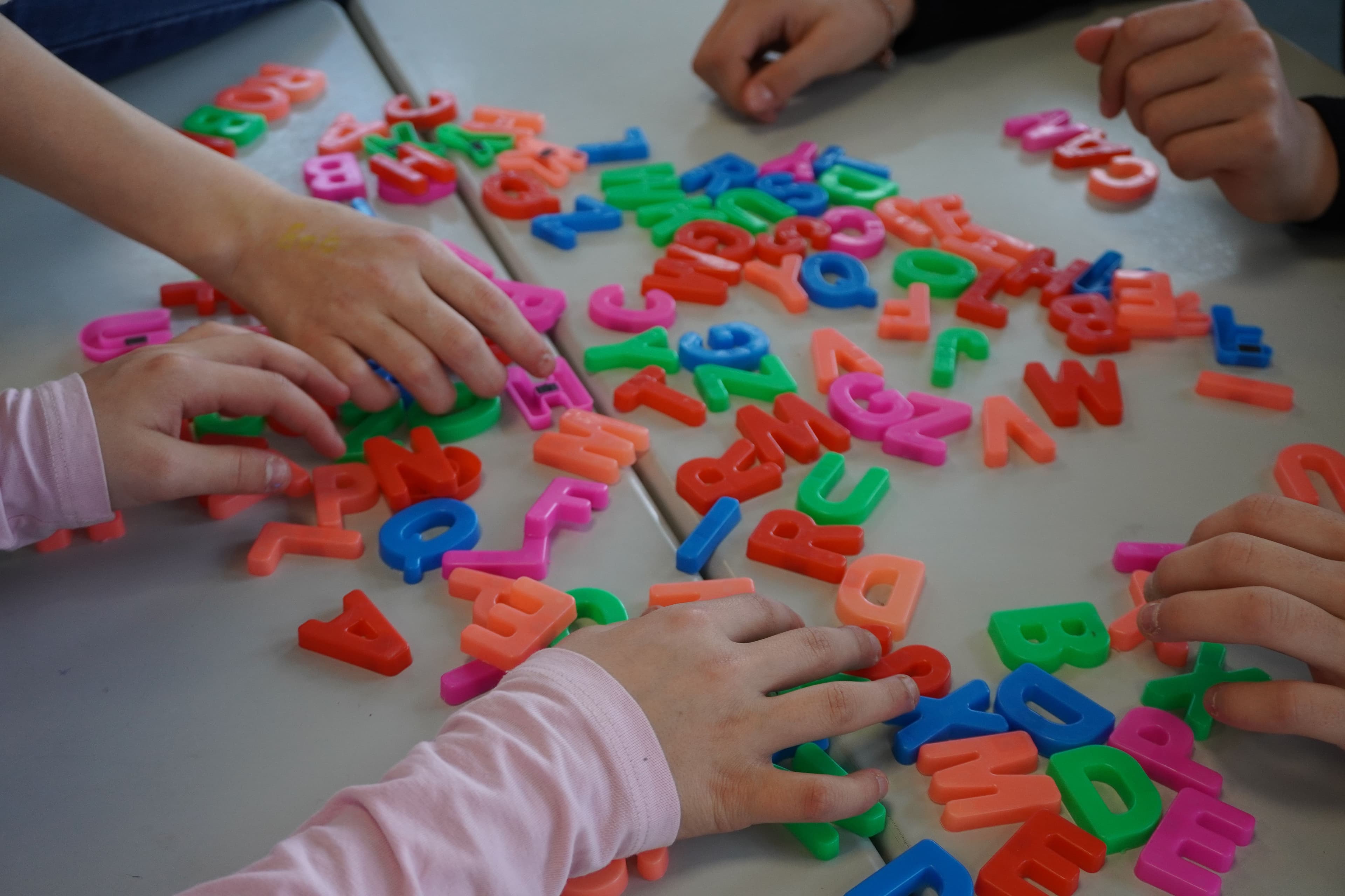 a group of children are playing with magnetic letters on a table .