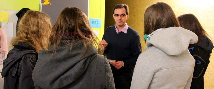 mehrere Menschen stehen um einen Mann herum, der etwas zu erzählen scheint