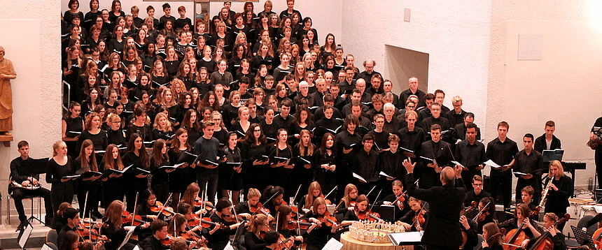 Bühne mit Menschen und Dirigent beim Weihnachtskonzert mit Chor und Streichorchester