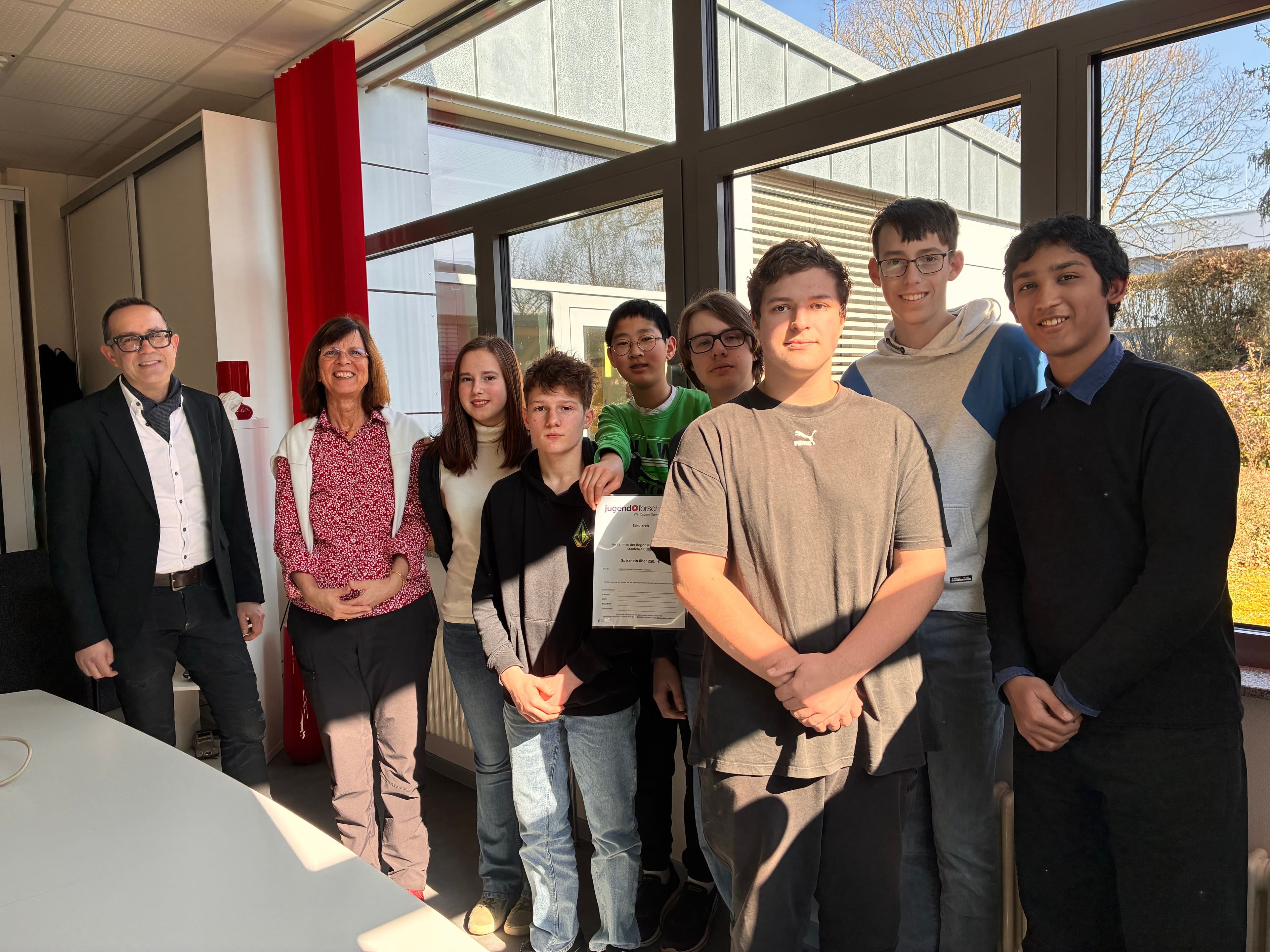 Two adults and seven students pose for a photo, one holding a certificate.