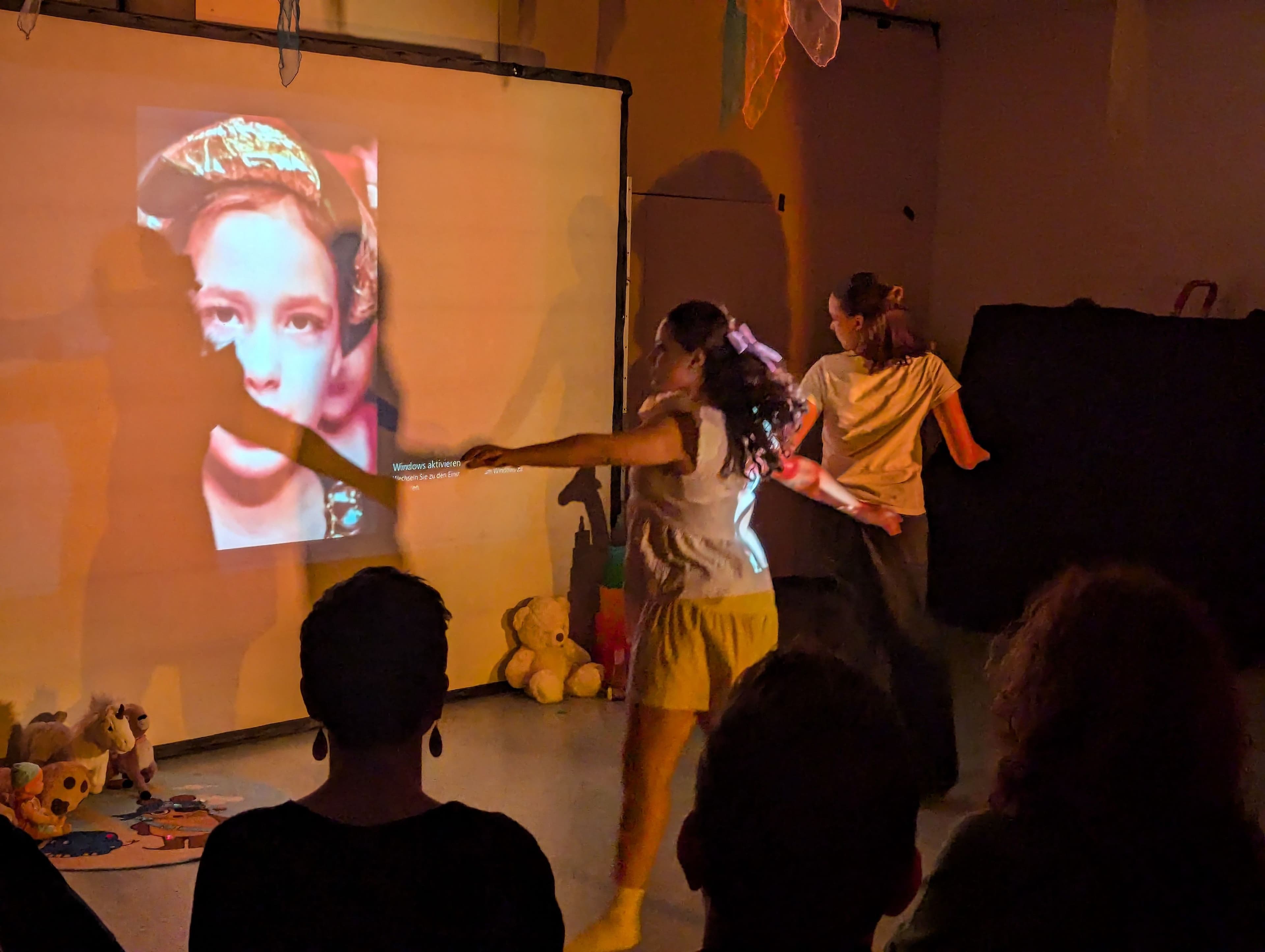 Tanzende mit Projektion auf einer Bühne und Publikum im Vordergrund