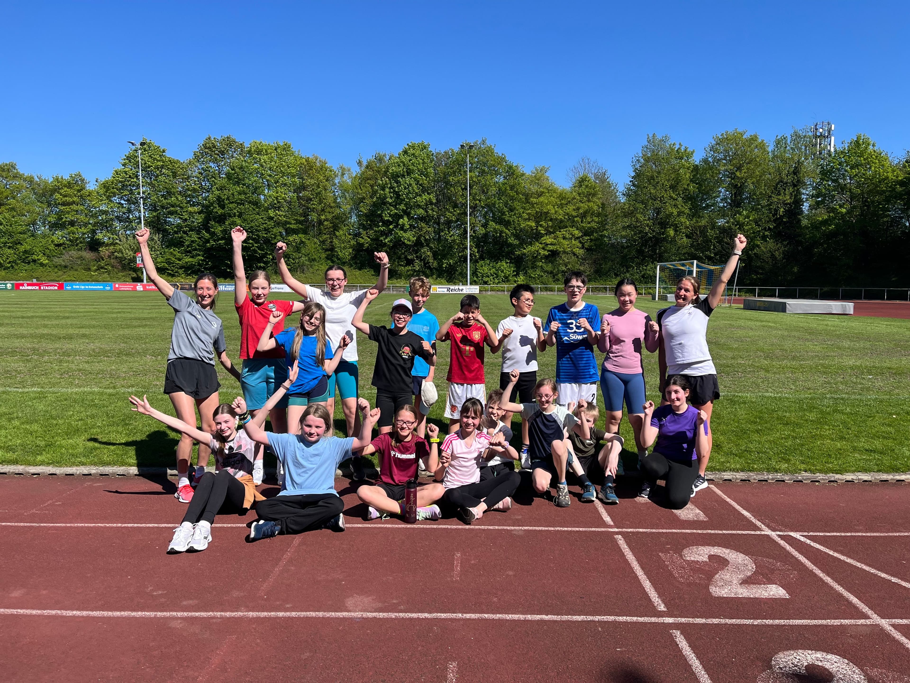 Excited youth and adults pose on a running track.