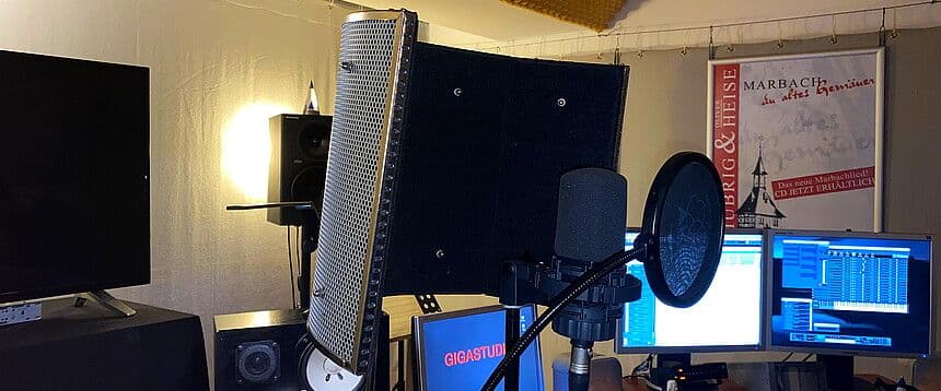 a microphone is sitting in front of two computer monitors in a recording studio .