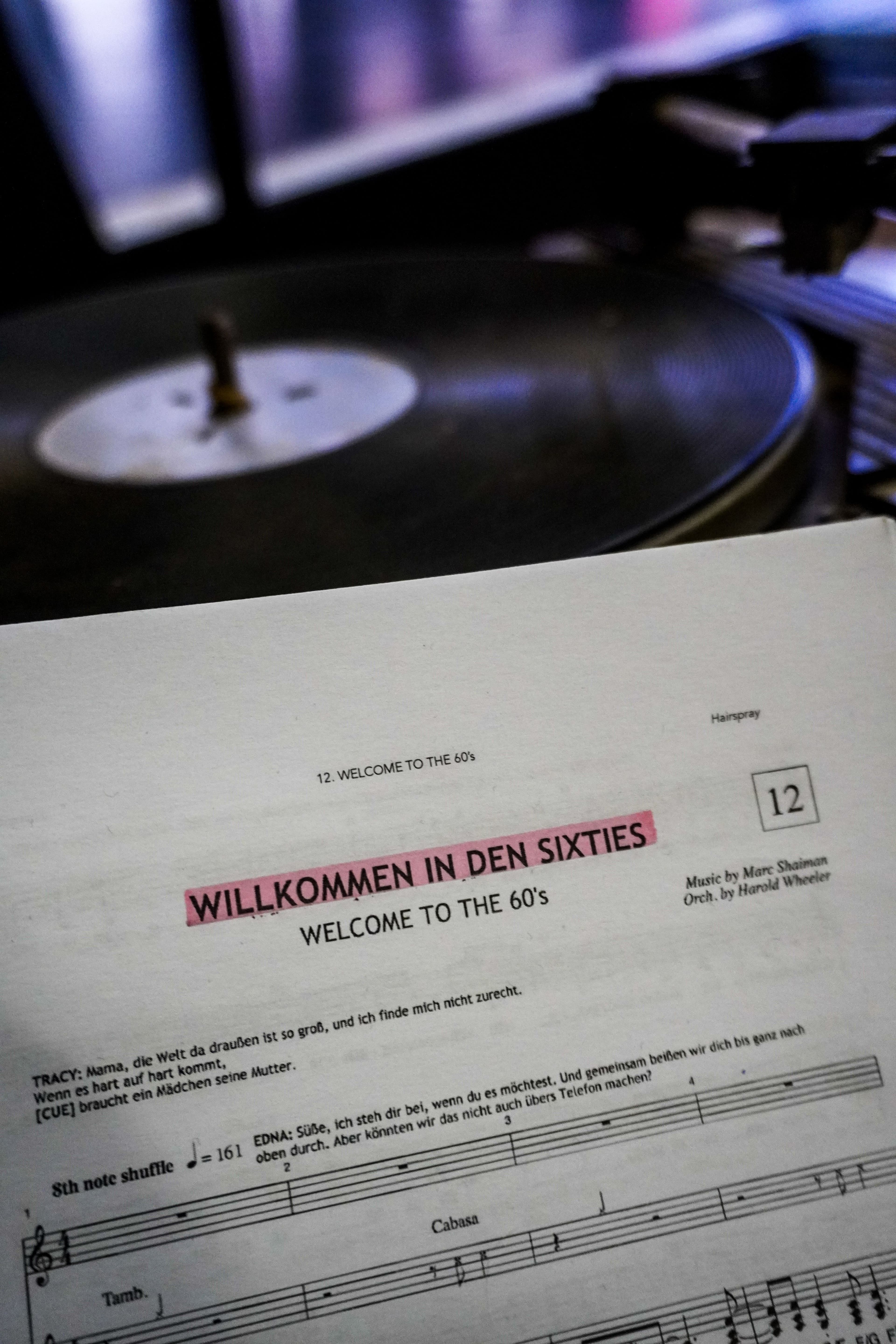 Im Vordergrund ein Textheft mit Noten, im Hintergrund eine alte Schallplatte.