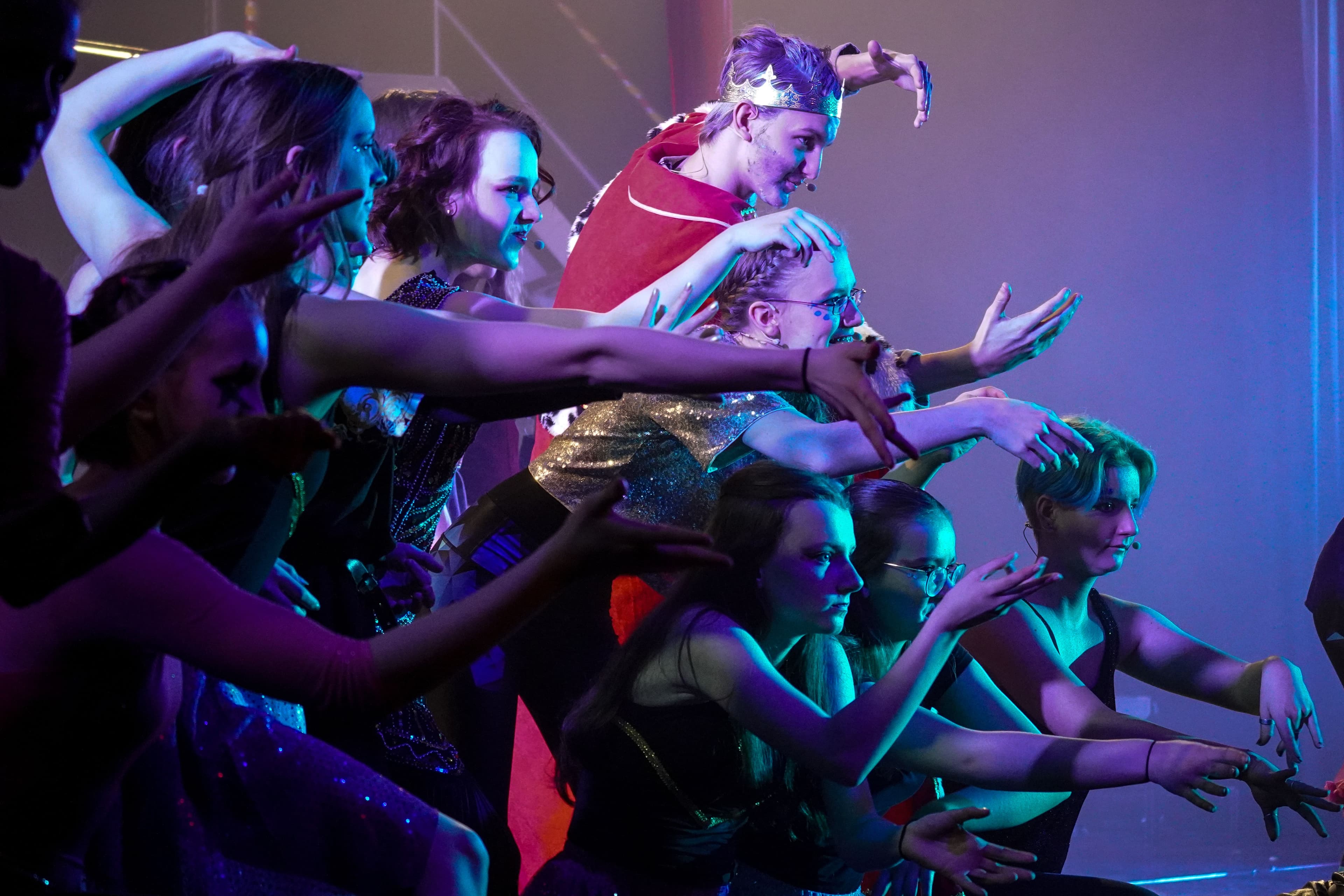 Mehrere Personen strecken blau beleuchtet ihre Arme nach etwas aus