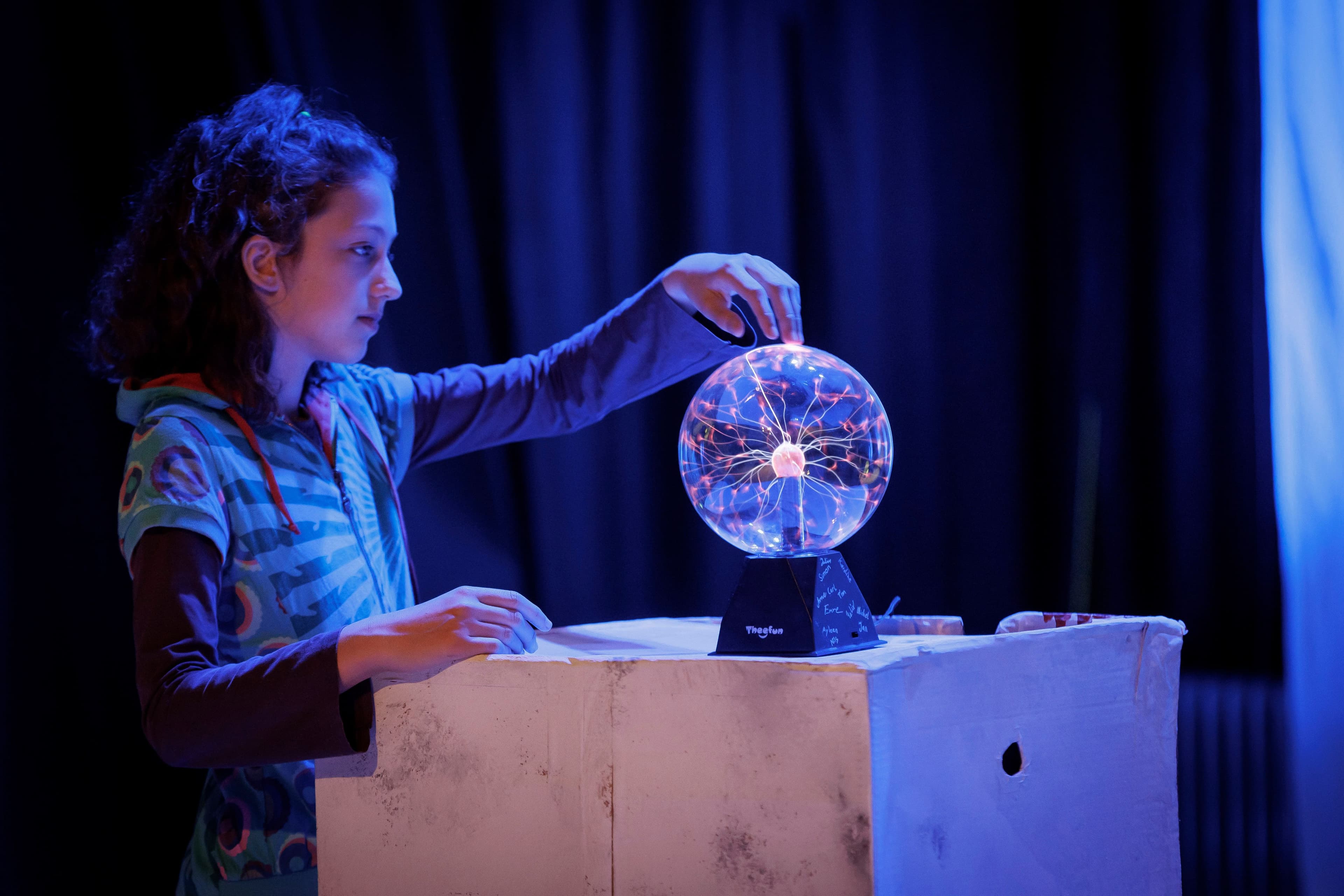 a young girl is playing with a plasma ball on a stage .