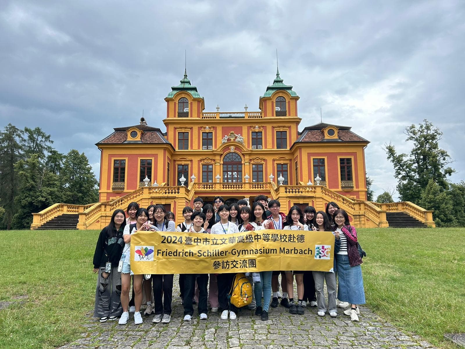 Schülerinnen und Schüler aus Taiwan mit Plakat vor einem Schloss.