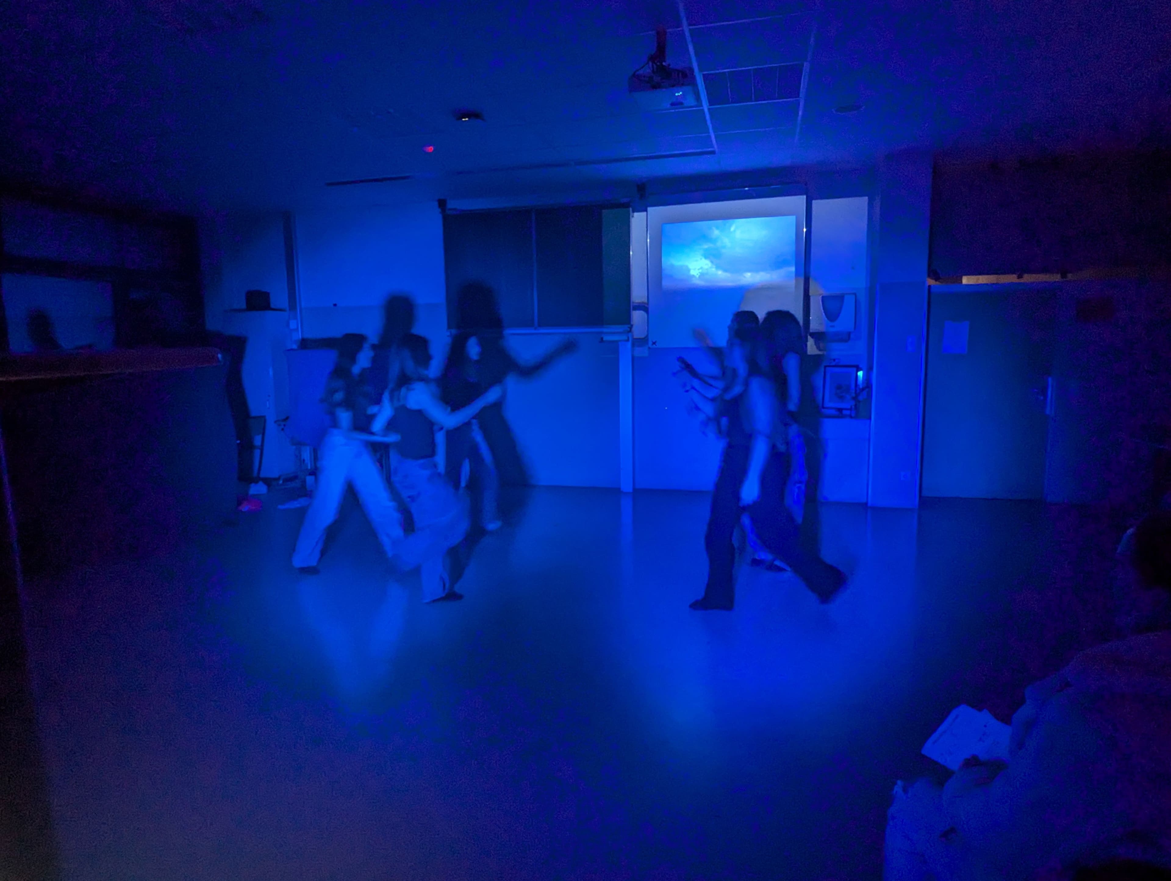 Tanzende Personen in einem blau beleuchteten Raum